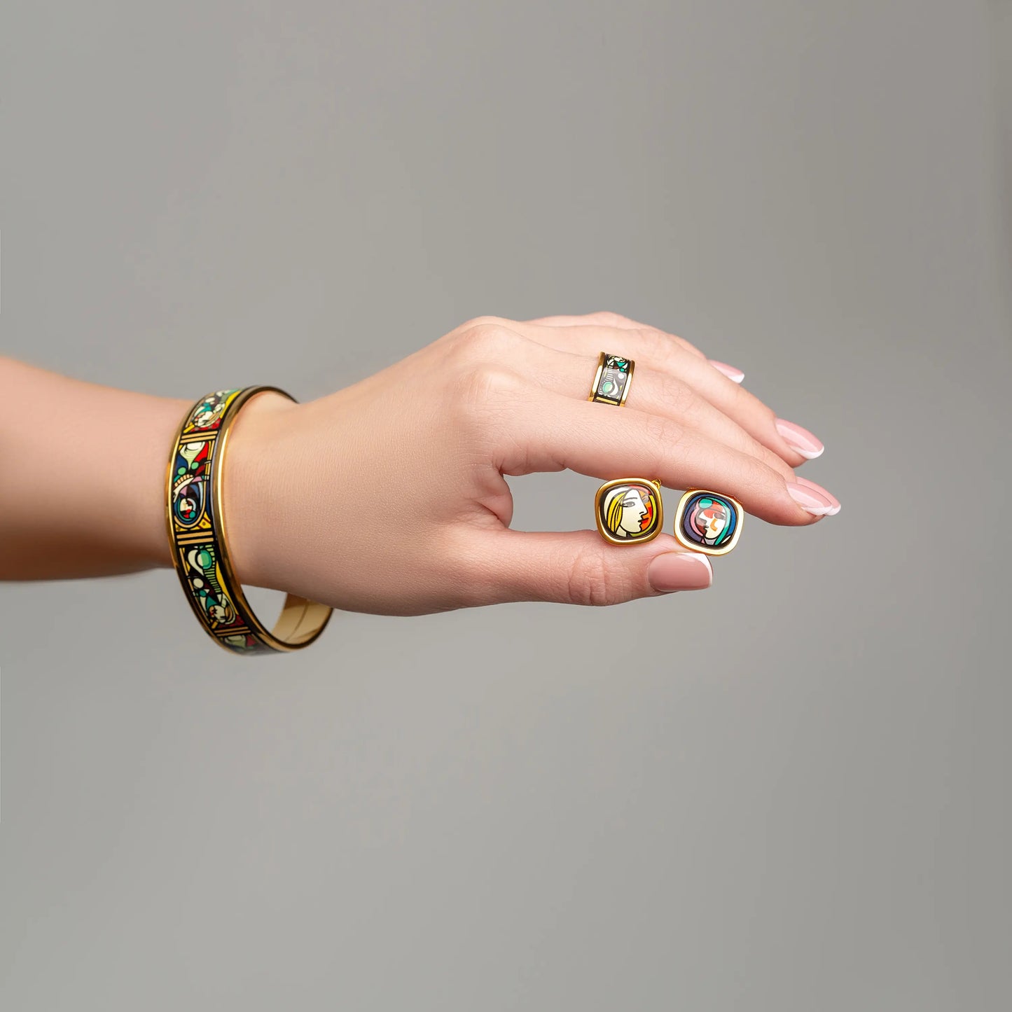 A hand with a bracelet and a ring holds earrings  from the Picasso's Secret collection.