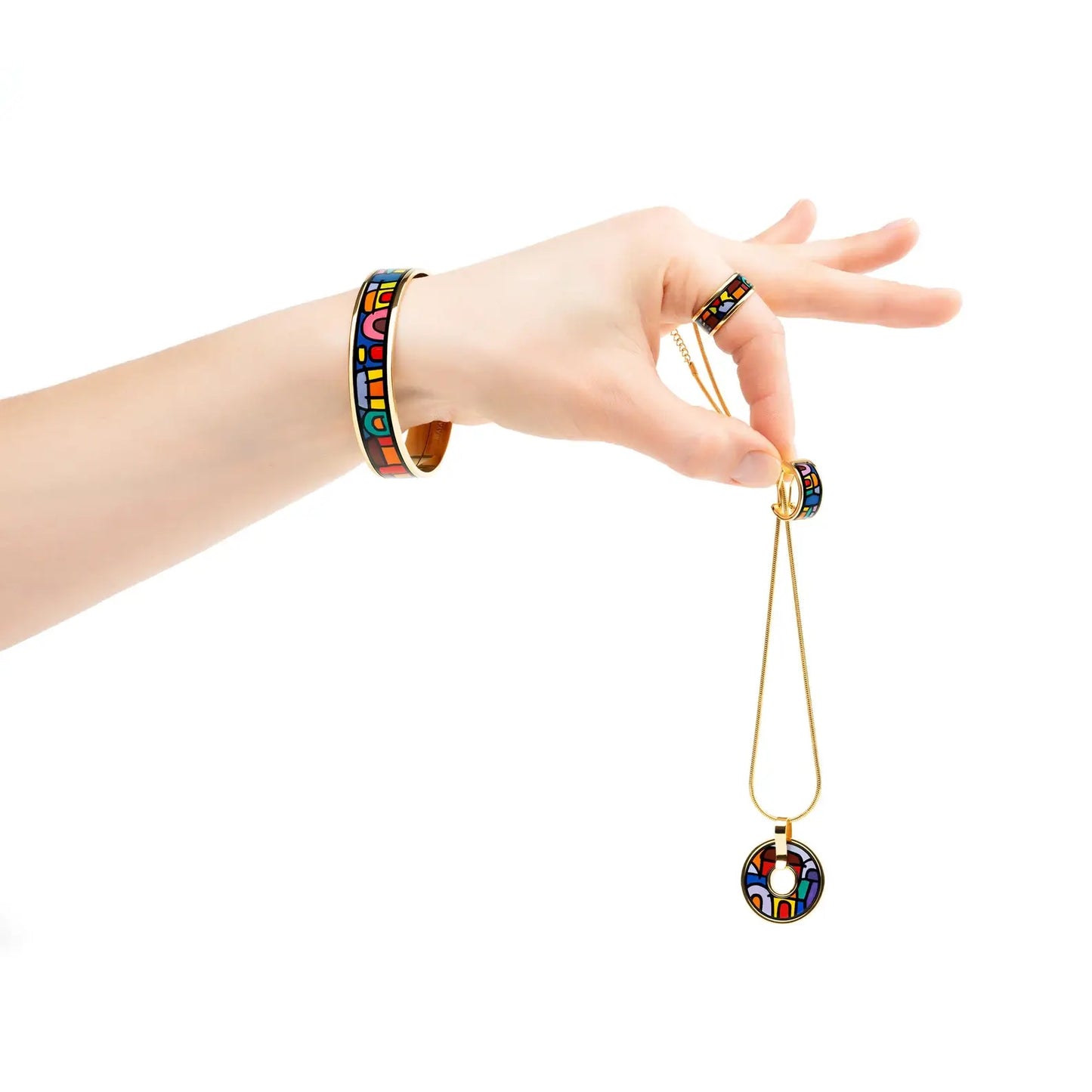 Hand with a bracelet and a ring are holding earrings and a round necklace from the Spanish Nights collection